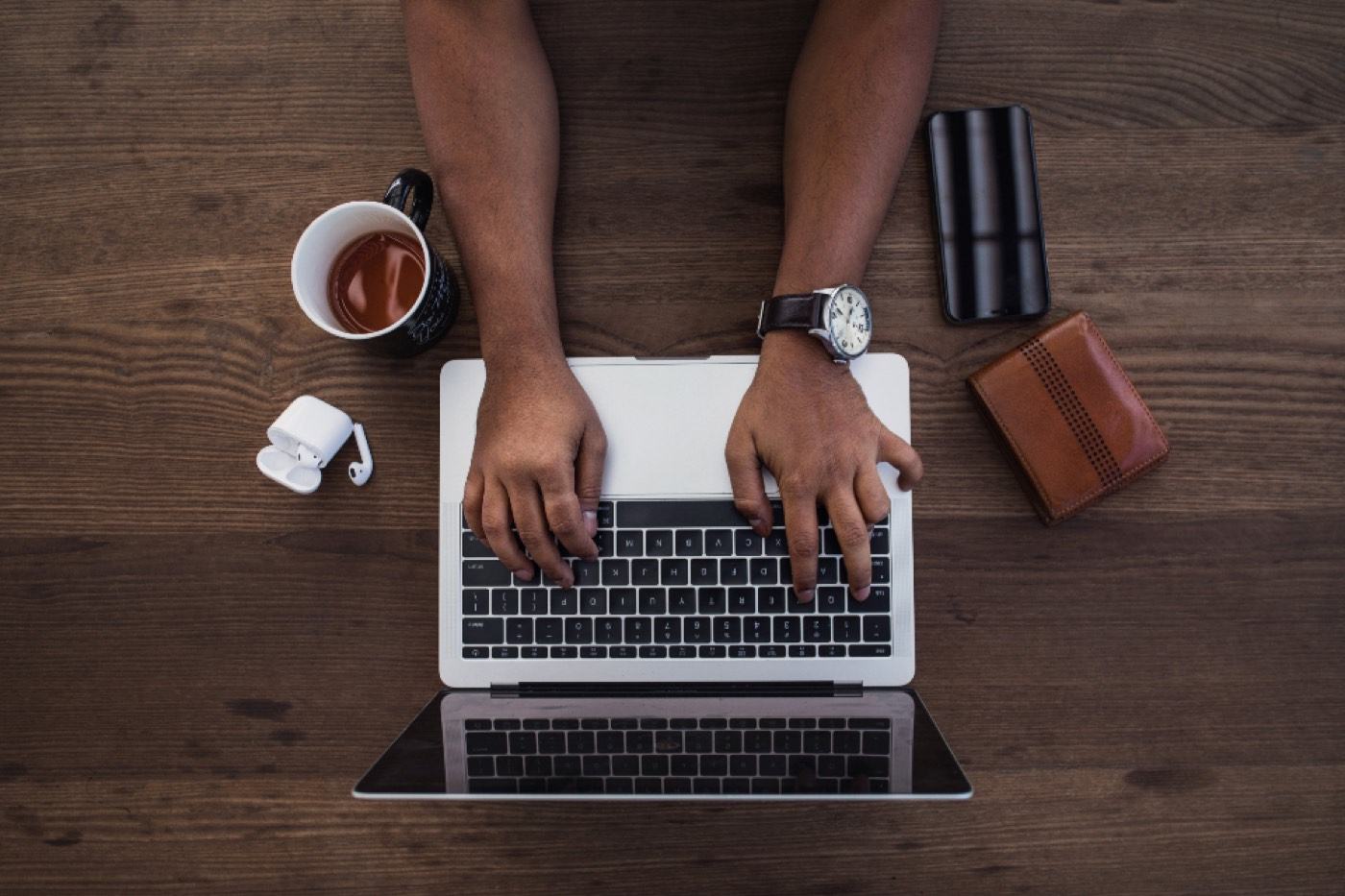Overhead view of a person typing on a laptop at a wooden desk